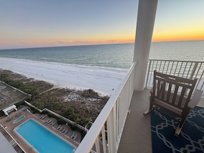 Ein Balkon mit Blick auf den Strand und den Ozean bei Sonnenuntergang.