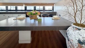 Een moderne keuken met een groot eiland, witte kasten en een hangende lamp.