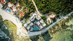 An aerial view of a coastal resort with multiple villas, a central pool area, and a beach. - BT Homes - Tankah Luxe (Tulum)