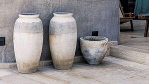 Two large vases on a tiled patio, a modern building entrance, and a glimpse of the interior. - BT Homes - Tankah Luxe (Tulum)