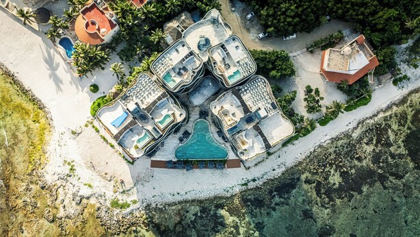 An aerial view of a resort with multiple swimming pools, a large central pool, and a beach area. - BT Homes - Tankah Luxe (Tulum)