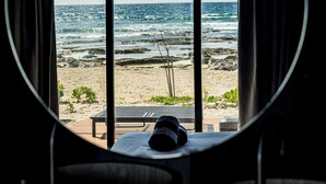 A circular mirror reflecting a beach view with a bench and a hat on it. - BT Homes - Tankah Luxe (Tulum)