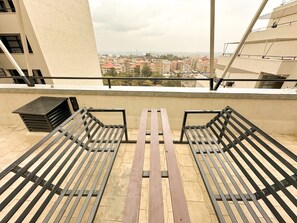 A rooftop terrace with two wooden benches and a small trash bin. - Clean Modern 1BR near TRM Mall off Thika Road
Perfect for long and Short stays. (Nairobi)