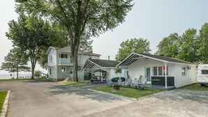 A two-story motel with a covered porch and outdoor seating. - Le Repere du Lac - Lake View, Access, beach & Spa (Venise-en-Québec)