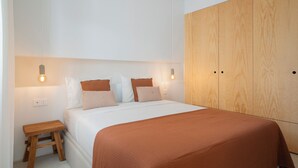 A bedroom with a bed, wooden wardrobe, and bedside lamps. - With patio, in Funchal city centre - AL'gria I (Funchal)
