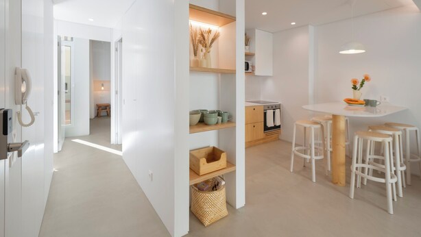 A modern kitchen with white cabinetry, a central island with stools, and a dining table. - With patio, in Funchal city centre - AL'gria I (Funchal)