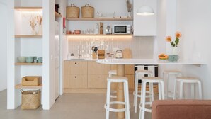 A modern kitchen with white cabinetry, wooden countertops, and bar stools. - With patio, in Funchal city centre - AL'gria I (Funchal)