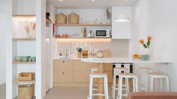 Une cuisine moderne avec des meubles blancs, des plans de travail en bois et des tabourets de bar.