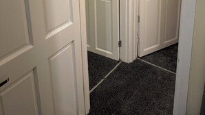 A hallway with white doors, carpeted floor, and a light switch on the wall. - 3-Bed Home, Free Parking, Smart TV,Family & Business Ready (Slough)