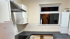 A compact kitchen with white cabinets, a black countertop, and a window above the sink. - 3-Bed Home, Free Parking, Smart TV,Family & Business Ready (Slough)