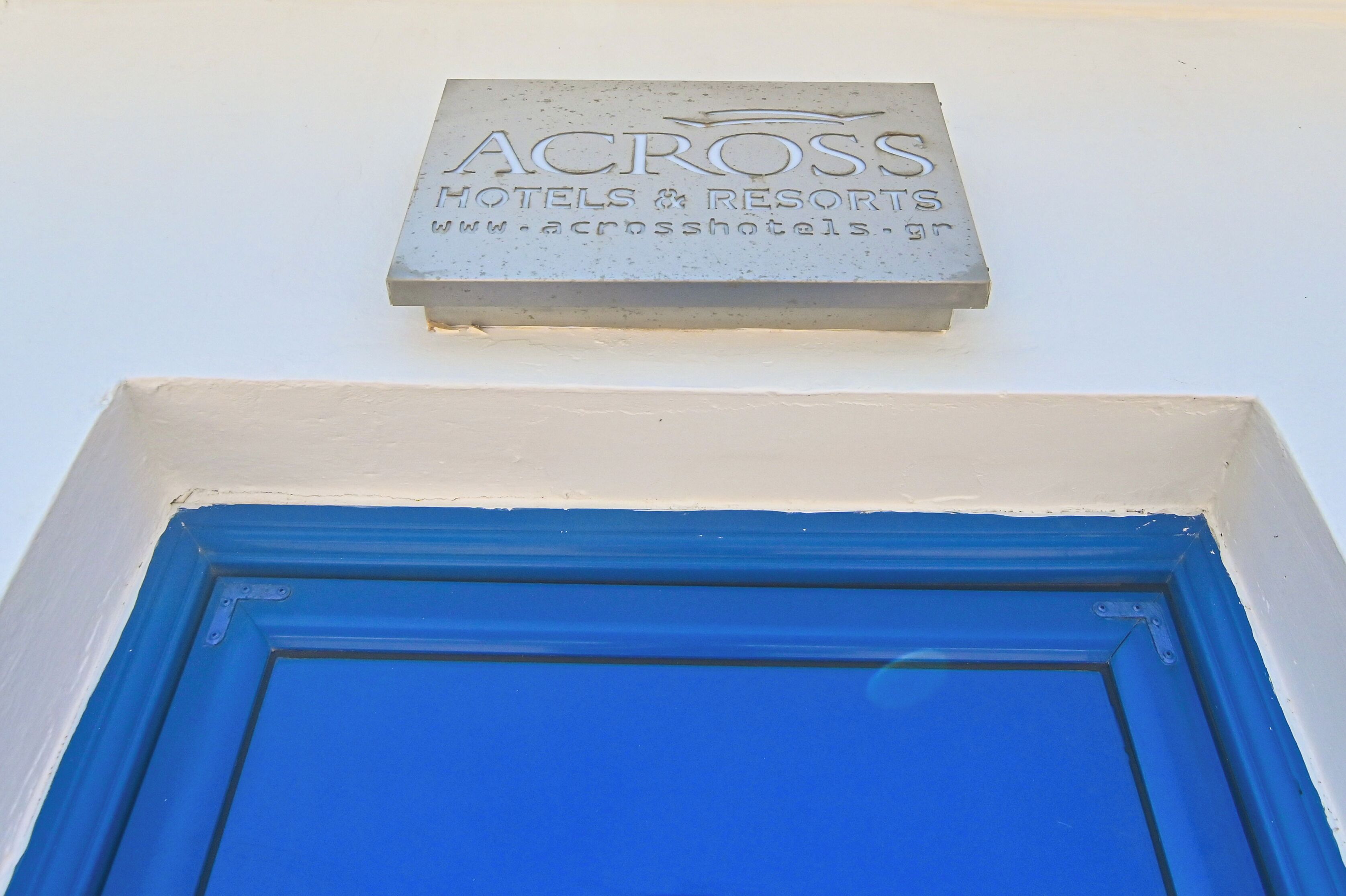 A sign for 'ACROSS HOTELS & RESORTS' with a blue door below.