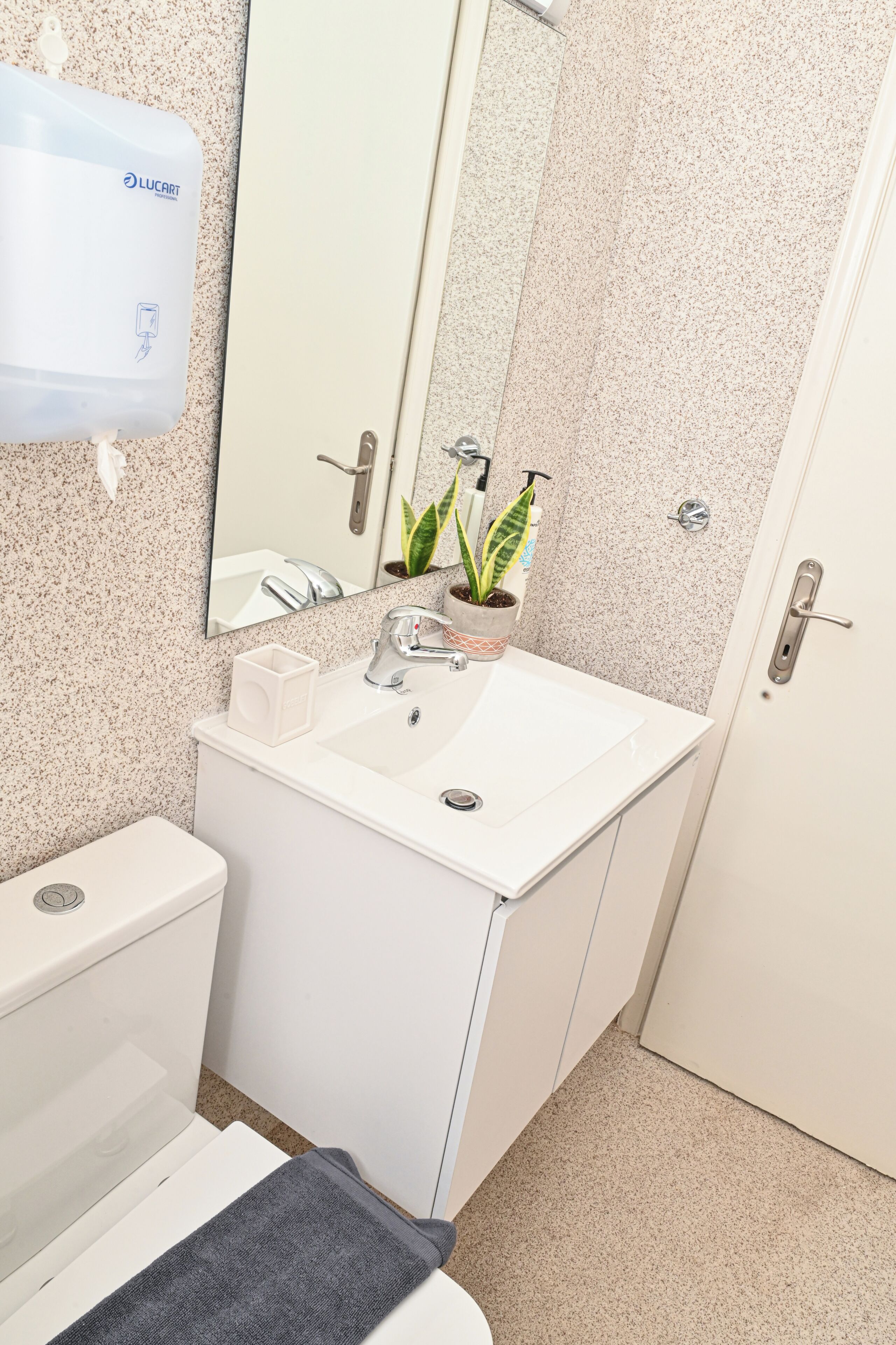 A bathroom with a white sink, mirror, and toilet.