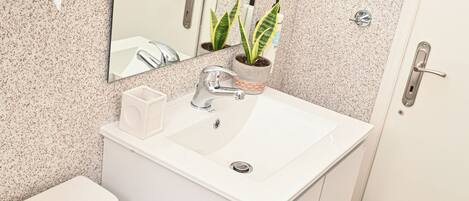 A bathroom with a white sink, mirror, and toilet.