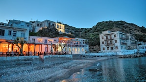 A coastal building with multiple balconies, a waterfront view, and a hillside backdrop.