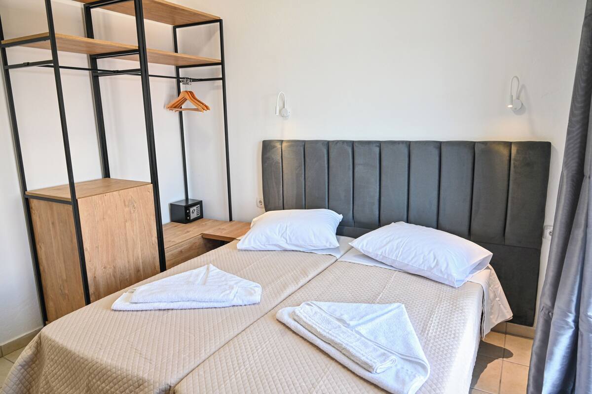 Ein Hotelzimmer mit Bett, einer Holzregaleinheit und einer Kleiderstange.