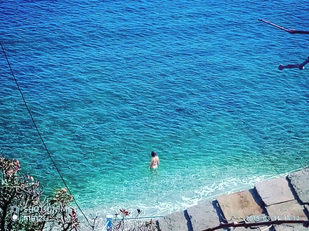 Une personne nage dans une eau d’un bleu cristallin.