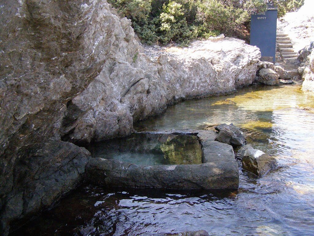 A rocky water feature with a stone structure, surrounded by natural vegetation.