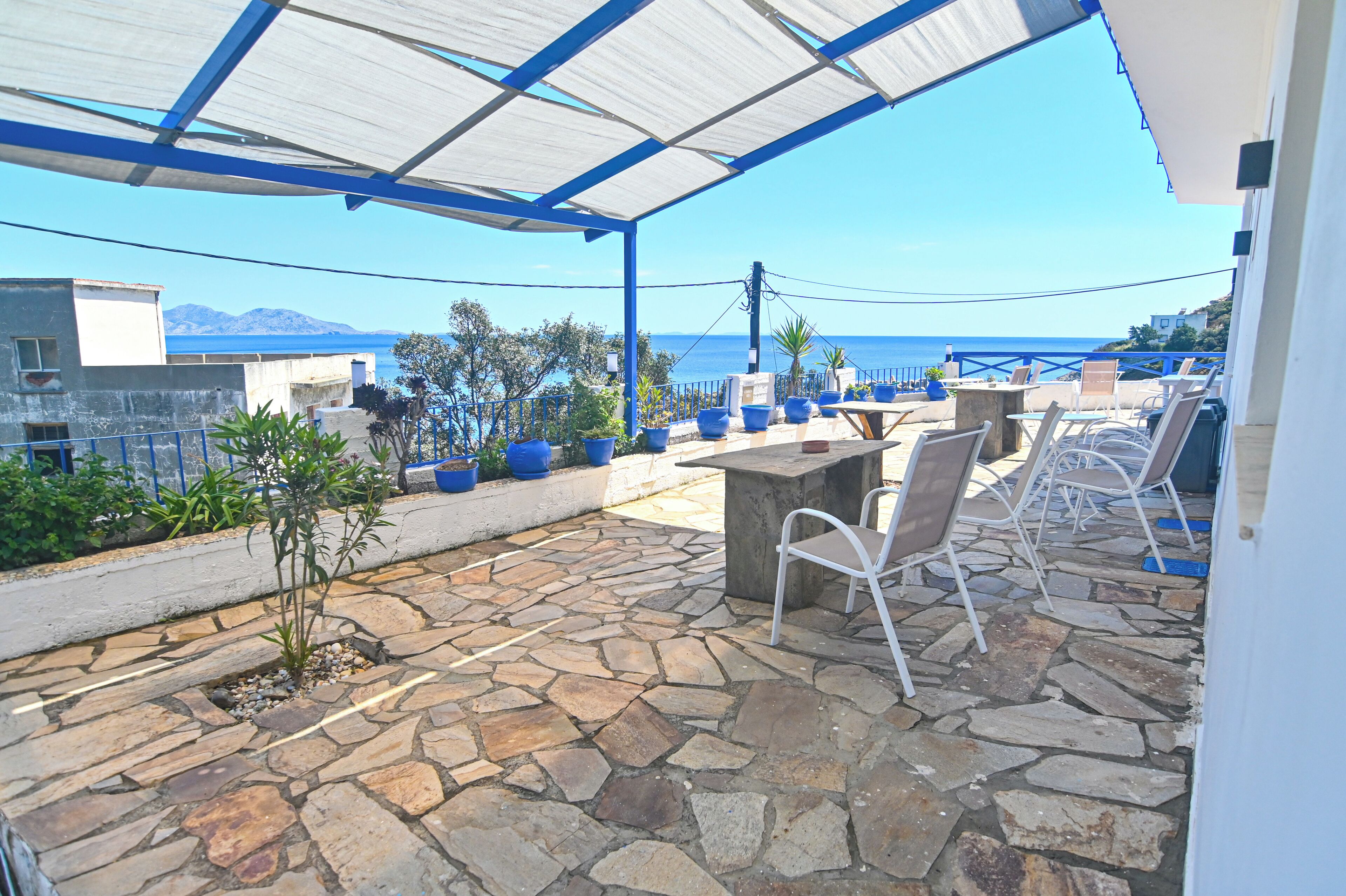 A covered outdoor area with stone flooring, potted plants, and outdoor seating.