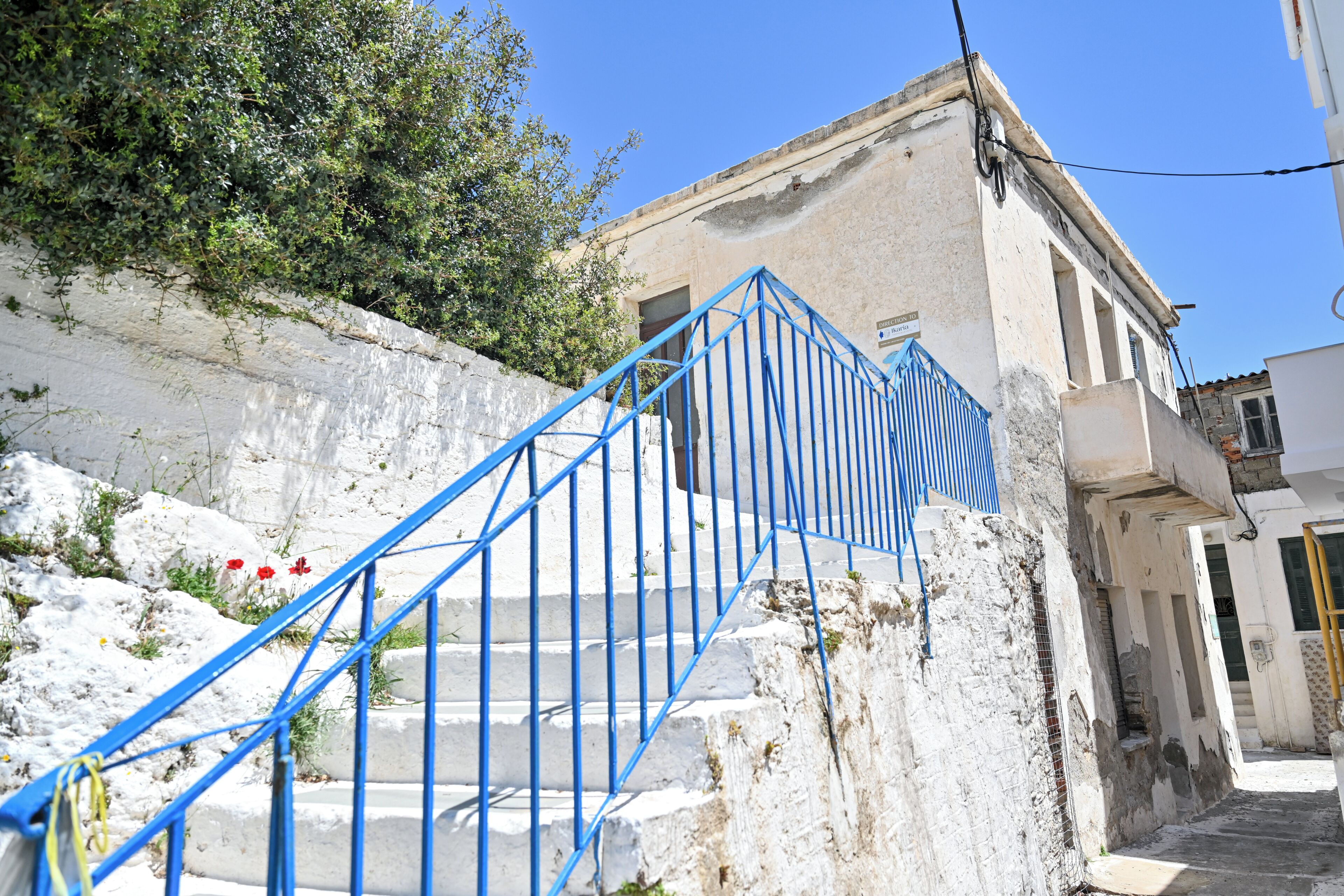 A staircase with blue railings leading up to a building with a white facade and a door.