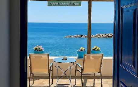 A view from a balcony with a pergola, a table, two chairs, and potted plants.