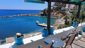 A terrace with a view of a coastal area, including a marina and buildings in the background.