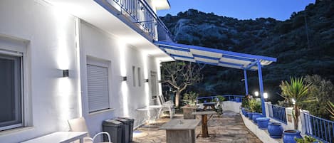 Une terrasse en pierre avec des meubles d’extérieur, un espace salon abrité et des plantes en pot.