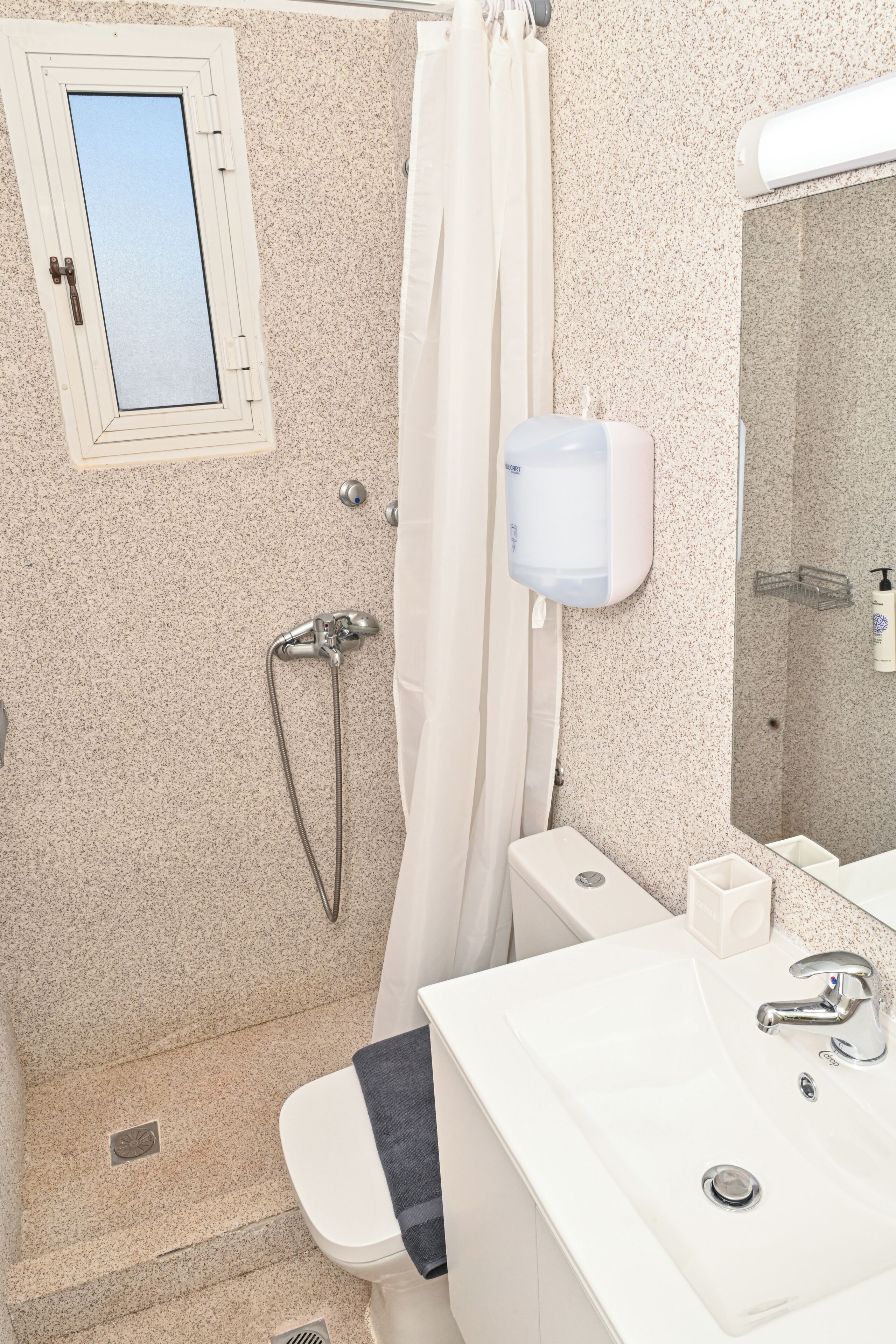 Une salle de bain équipée d’une douche, de toilettes, d’un lavabo et d’un miroir.