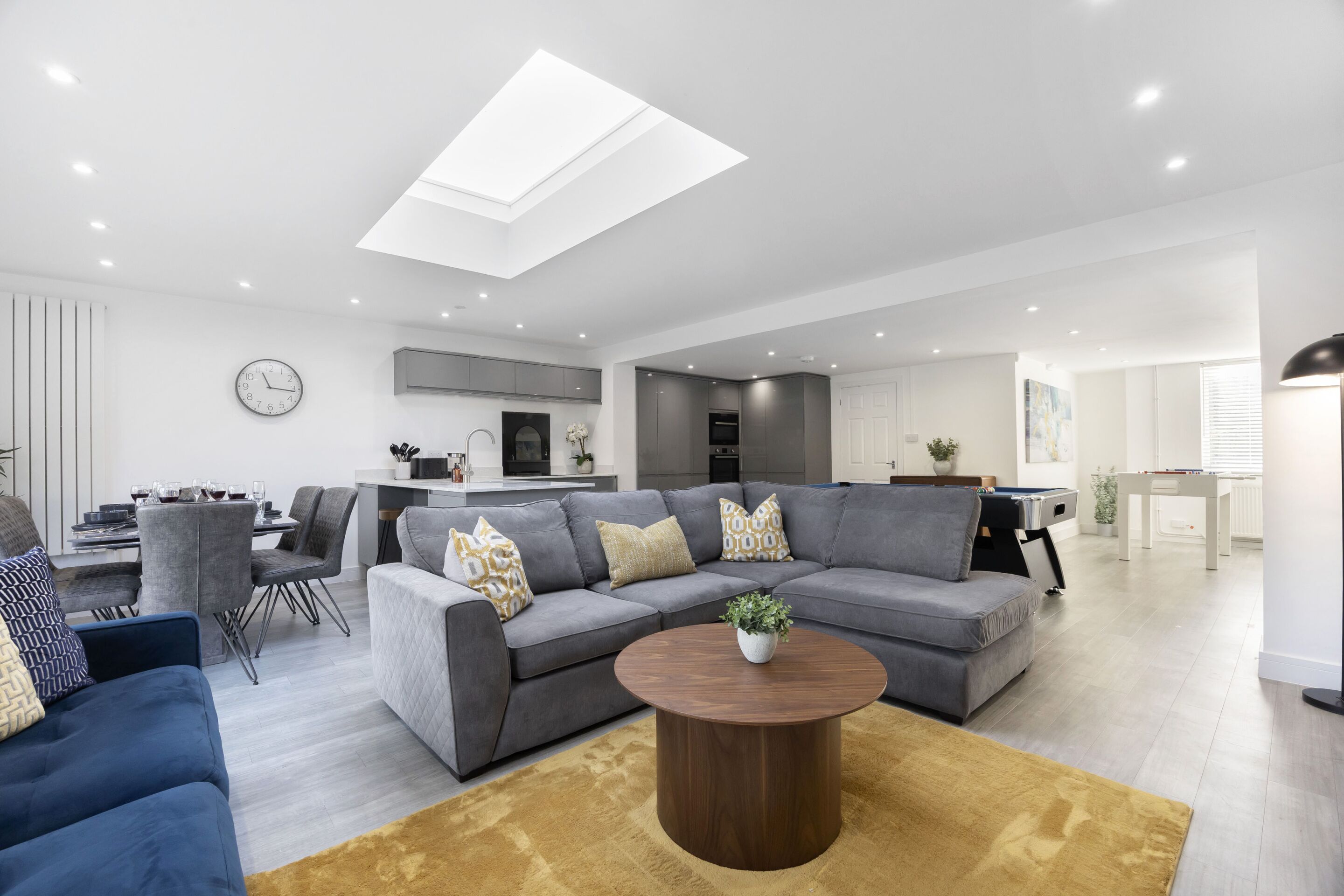 A modern living room with a sectional sofa, a coffee table, and a dining area with a table and chairs.