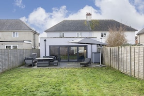 A house with a patio area featuring outdoor furniture and a large umbrella. - Fantastic 3 Bedroom Home in Gloucester City (Gloucetser)