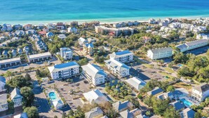 An aerial view of a coastal resort area with multiple buildings, including a large hotel with a swimming pool and a beach in the background. - Chic condo@Hidden Lake~Santa Rosa Beach ~Sleeps 6! (Santa Rosa Beach)