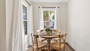 A dining area with a round wooden table, four wooden chairs, and a potted plant. - Chic condo@Hidden Lake~Santa Rosa Beach ~Sleeps 6! (Santa Rosa Beach)