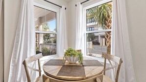 A corner room with two windows, a wooden table with a woven placemat, and a potted plant. - Chic condo@Hidden Lake~Santa Rosa Beach ~Sleeps 6! (Santa Rosa Beach)