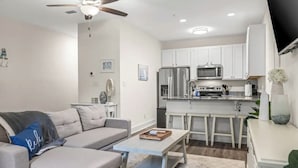 A modern kitchen with white cabinets, a stainless steel refrigerator, and a microwave. There is a dining area with a white table and chairs. - 2 beach accesses in walking distance! ~1 bd/2ba on 30A~Sleeps 4! (Santa Rosa Beach)