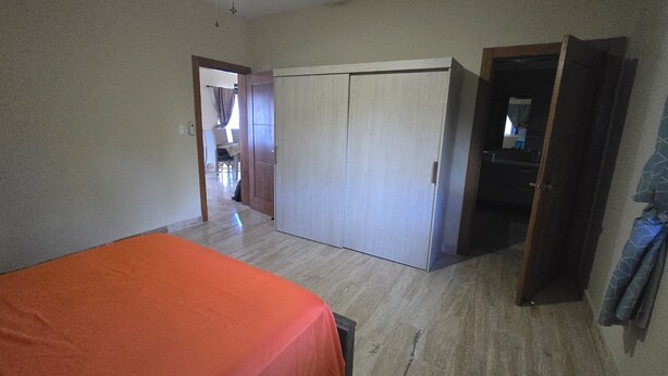 A room with a bed, a wardrobe, and a door leading to another room. - Beachfront Condo w/ Ocean View, Pool + Steps to Cabarete Beach (Cabarete)