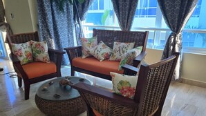 A seating area with wicker furniture and floral cushions. - Beachfront Condo w/ Ocean View, Pool + Steps to Cabarete Beach (Cabarete)