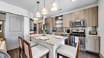 Una cocina moderna con una isla central, electrodomésticos de acero inoxidable y armarios de madera.