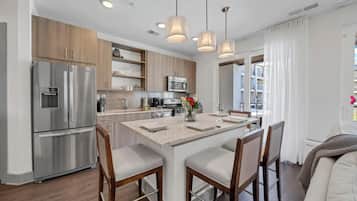 Una cocina moderna con electrodomésticos de acero inoxidable, una isla central con asientos e iluminación colgante.