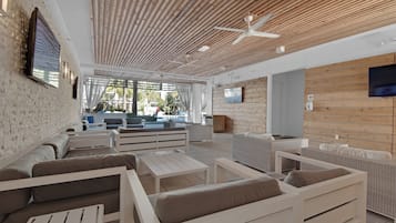 Een moderne zithoek met witte meubels, een houten plafond en een televisiescherm.