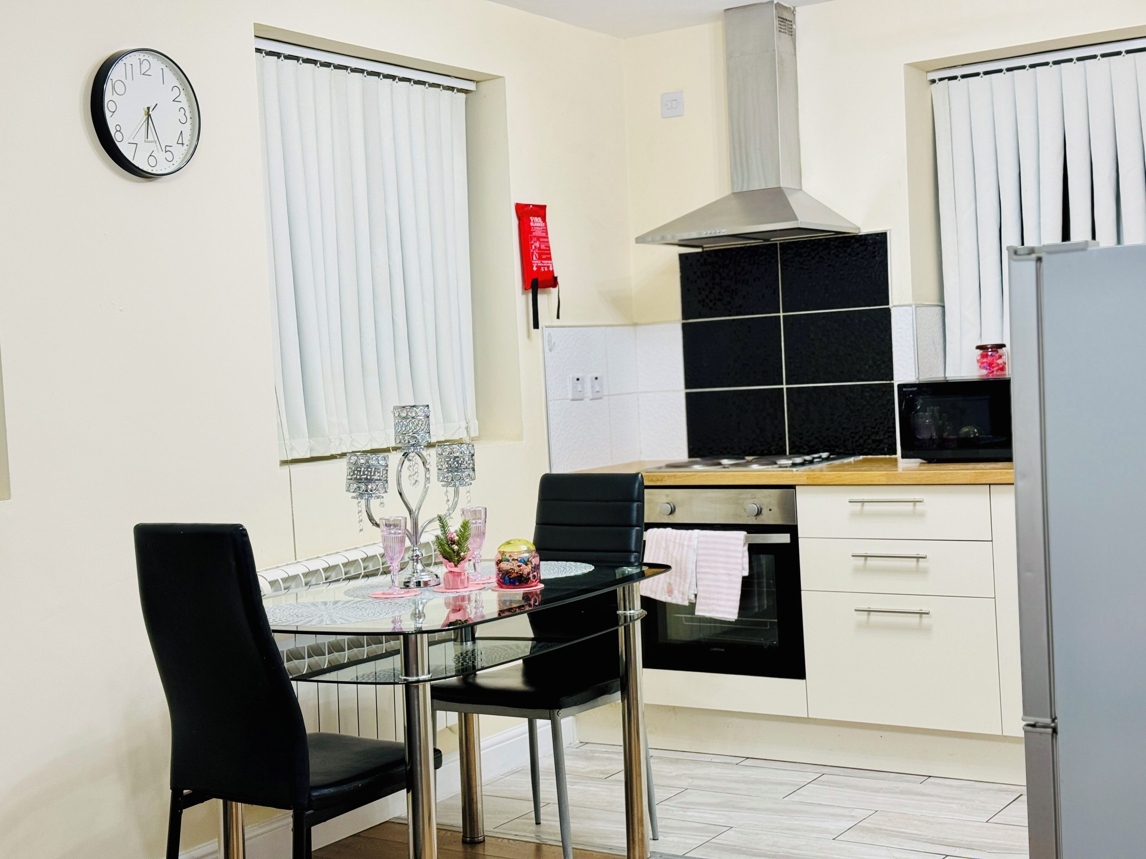 Una cocina moderna con una mesa de comedor, sillas, un reloj y una estufa.