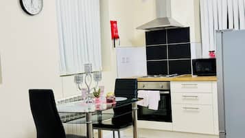 Una cocina moderna con una mesa de comedor, sillas, un reloj y una estufa.