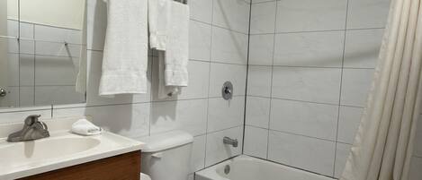 A bathroom with a toilet, sink, vanity, and bathtub.