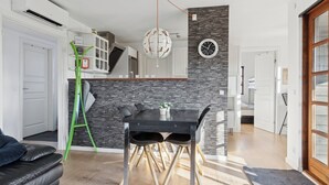 Cozinha moderna com mesa de jantar, escada e área de estar com sofá.