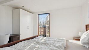 Quarto com cama, guarda-roupa, mesa de cabeceira e janela.