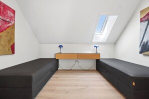 A room with a sloped ceiling, a skylight, a central wooden platform, and two black sofas. - Apartment with views close to the sea in Allinge (Allinge-Sandvig)