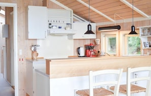 A compact kitchen with a coffee machine, a kettle, and a window with a view of greenery.