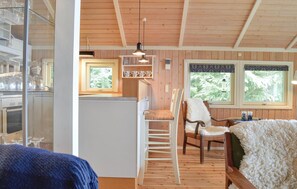 A cozy cabin interior with a kitchen area, a dining table, and a chair.