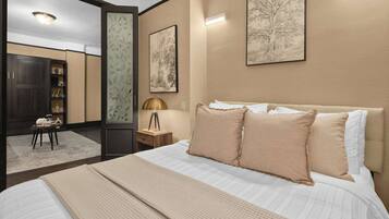 A bedroom with a large bed, a bedside table with a lamp, and two framed artworks on the wall.
