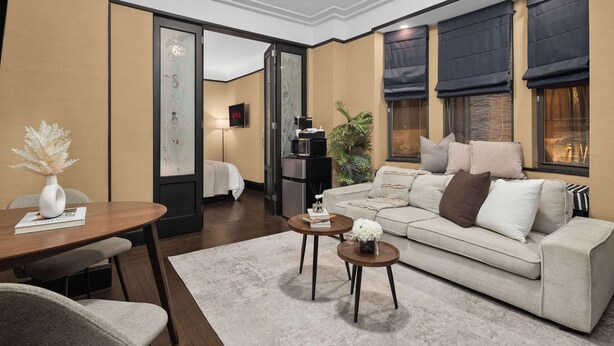 Een moderne woonkamer met een bank, twee salontafels, een eettafel en een televisie.