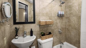Une salle de bain avec un lavabo blanc, un miroir, des toilettes, une douche et une étagère contenant des articles de toilette.