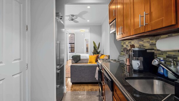 A modern kitchen with wooden cabinets, a black countertop, and a built-in oven.